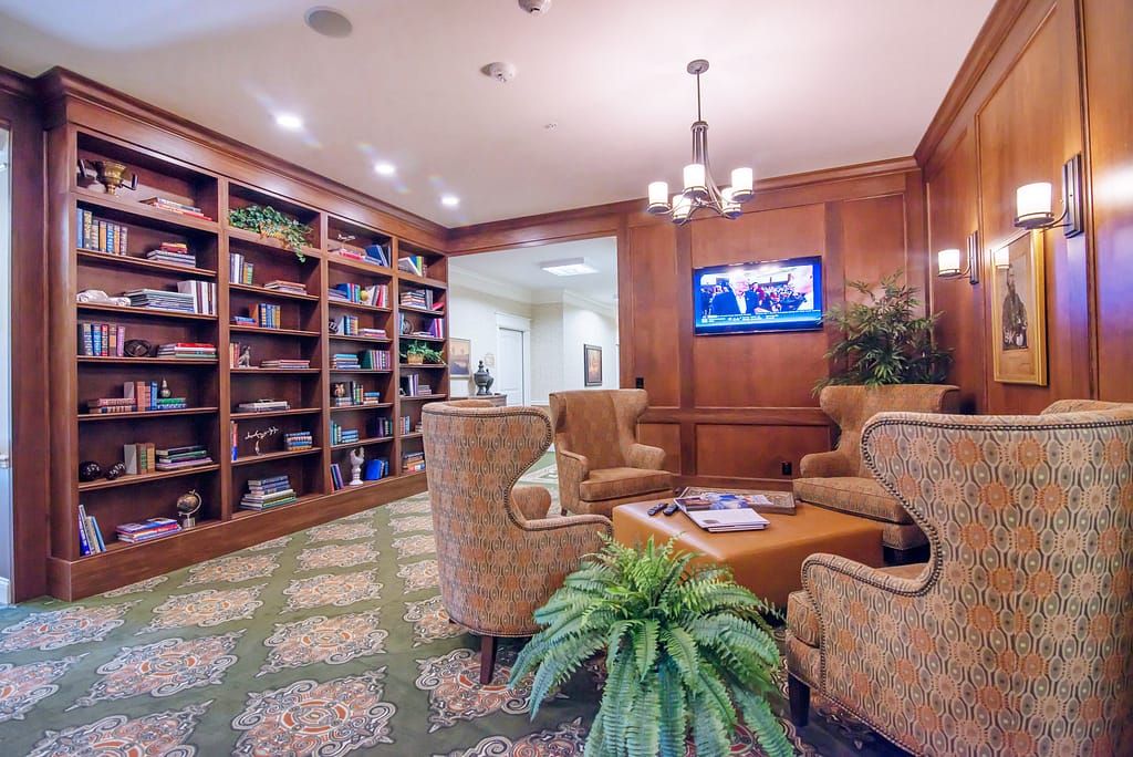 A cozy library room with comfortable seating, bookshelves, and a television.