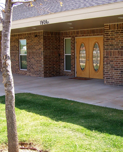 Entrance of a brick building with decorative double doors and well-maintained landscaping.