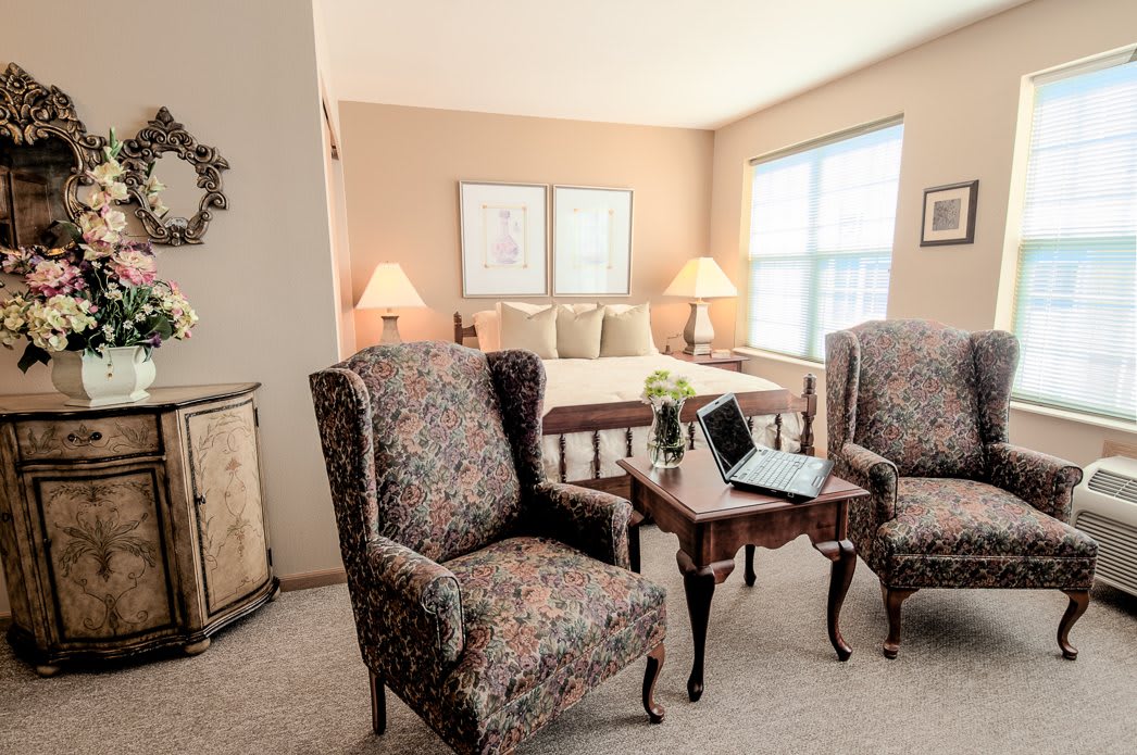 A cozy interior with two patterned armchairs and a wooden table in a warmly lit living area.