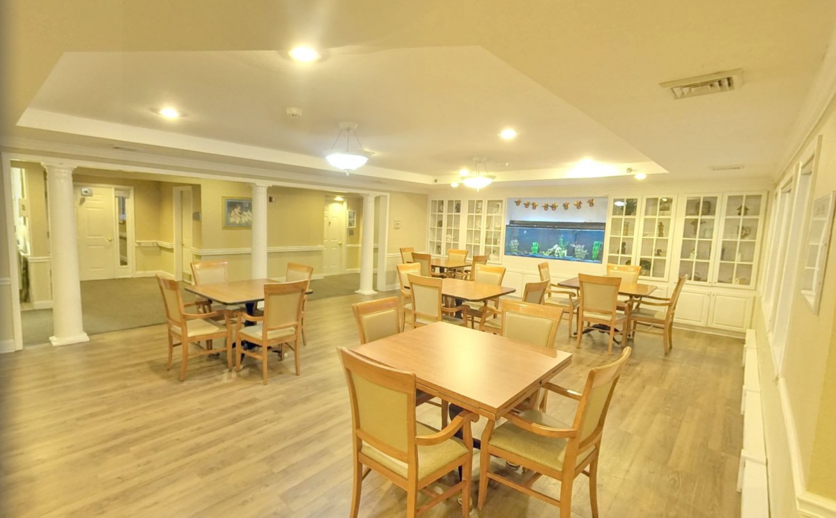 A spacious dining area with wooden tables and chairs, warmly lit.