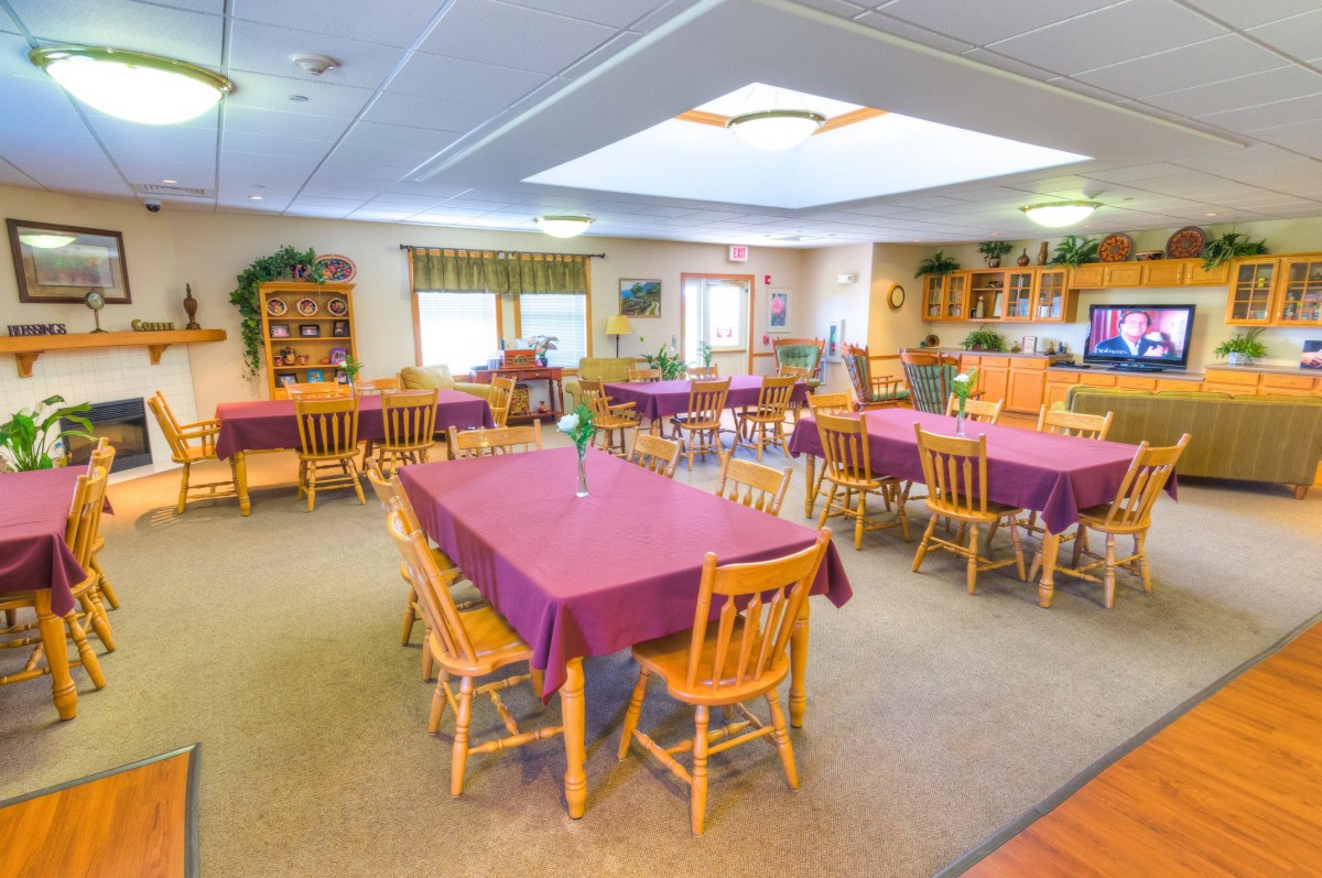 A cozy dining room with tables covered in purple tablecloths and wooden chairs.
