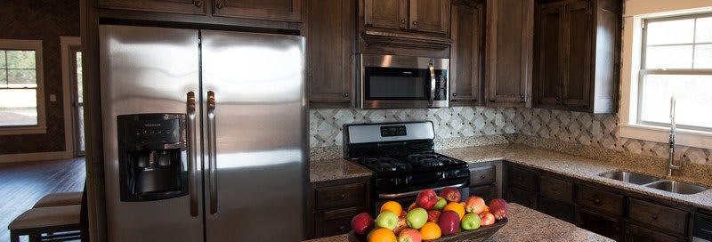 A modern kitchen with stainless steel appliances and a fruit bowl on the counter.