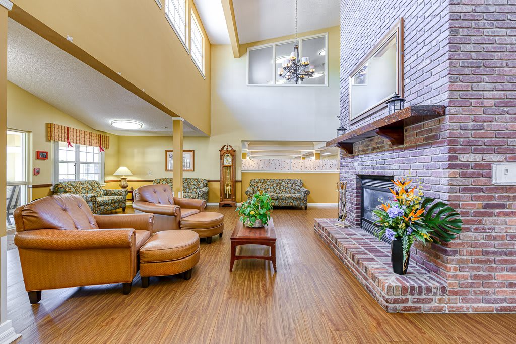 A spacious and cozy living room with a high ceiling, furnished with comfortable seating and a large brick fireplace.