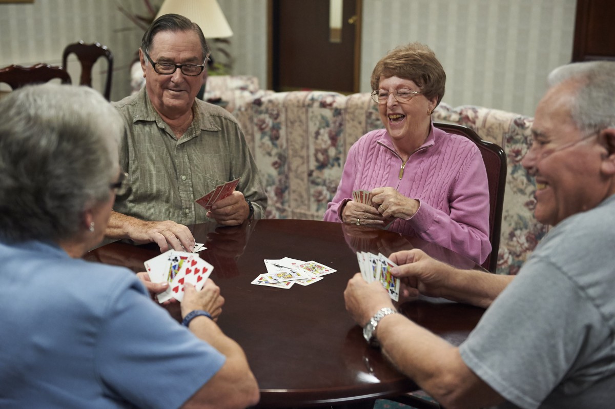 A group of seniors enjoying a card game together at a table indoors.