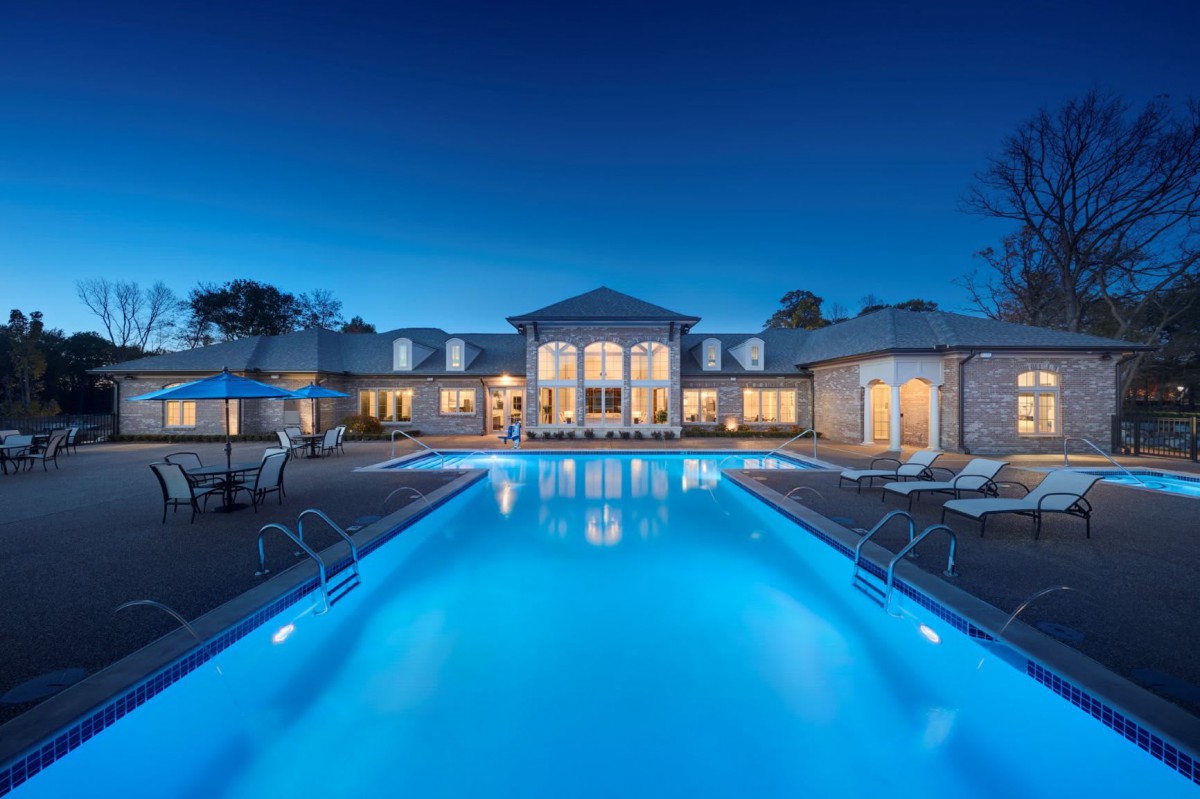 A luxurious mansion with a well-lit swimming pool under the night sky.