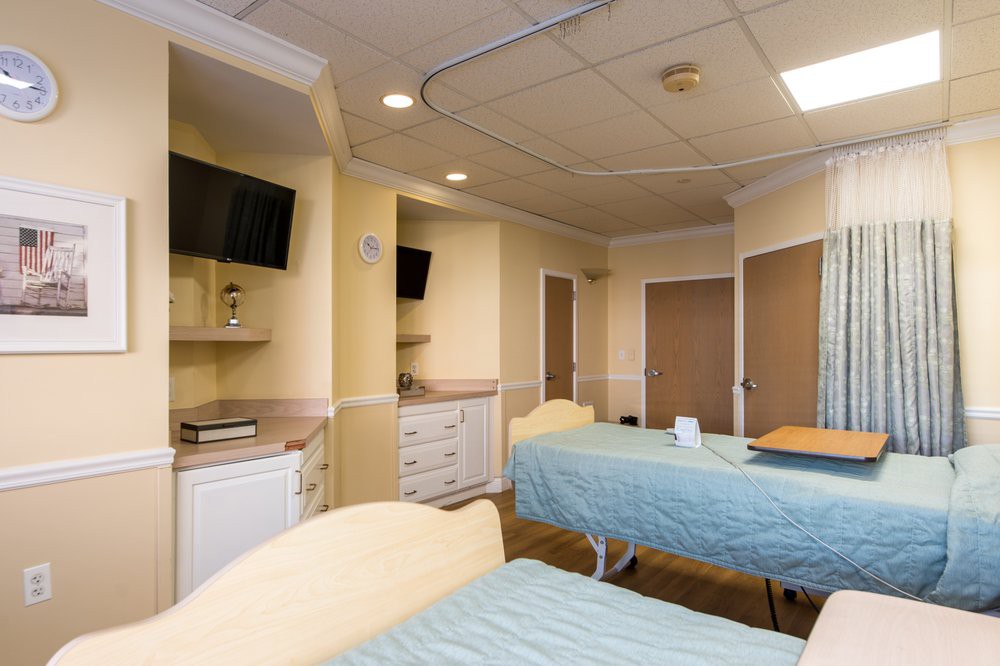 A hospital room with two beds, equipped with televisions and medical facilities.