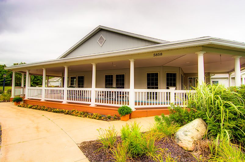 A charming house with a wraparound porch and neatly landscaped front yard.