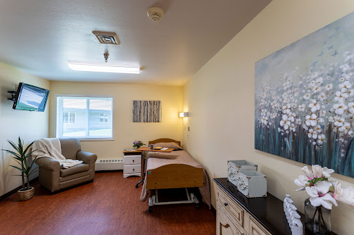 A well-lit hospital patient room featuring a bed, a cozy sofa, and decorative artwork.