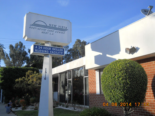 A commercial building with a prominent sign in front, surrounded by greenery on a clear day.