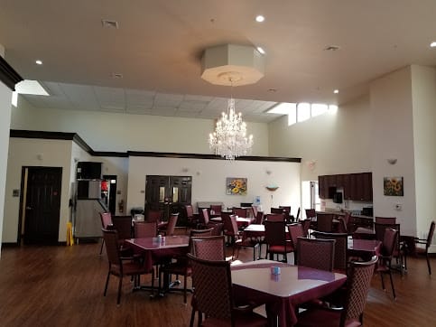 A spacious dining room with elegant chandeliers and neatly arranged tables and chairs.