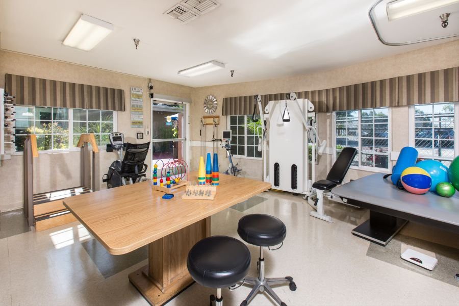 A well-equipped physical therapy room with various exercise machines and therapy tables.