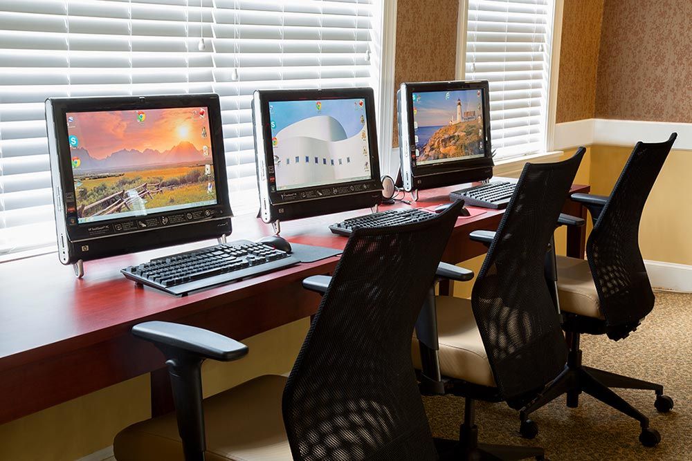 A row of computer workstations with chairs in an office setting.