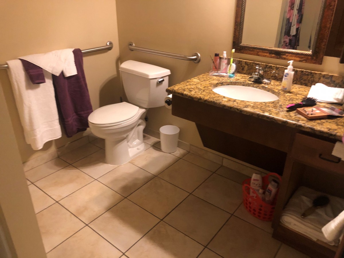 A clean bathroom with a toilet, sink, mirror, and towels.