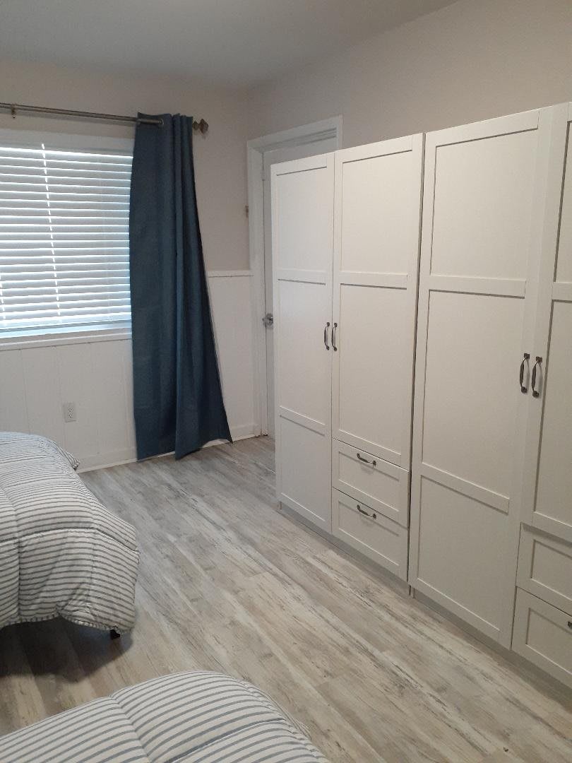 A minimalist bedroom with a large white wardrobe and blue curtains.