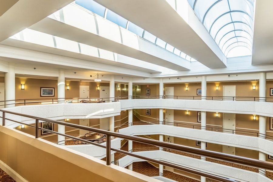 A modern, spacious atrium with multiple balconies and a skylight allowing natural light to flood the interior.