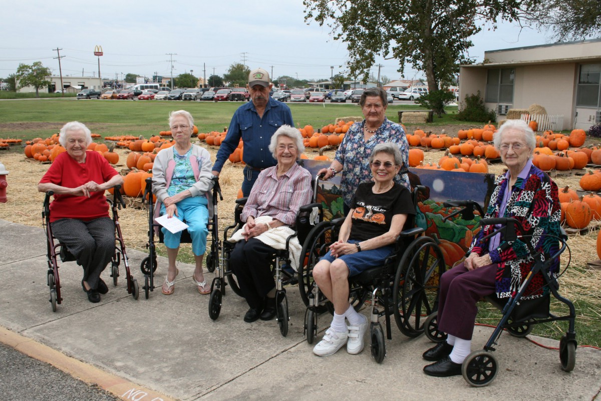 A group of seniors enjoying an outdoor autumn gathering surrounded by pumpkins.