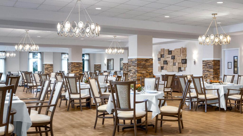 Elegant dining area with neatly arranged tables and chairs under beautiful chandeliers.