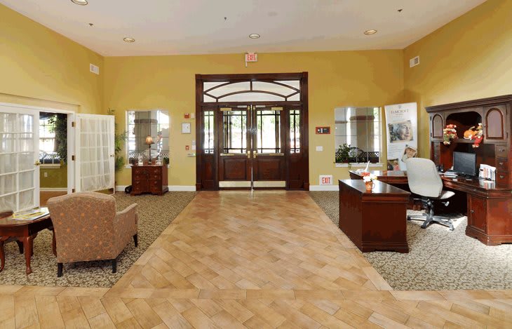 A spacious lobby with elegant wooden doors, desks, and comfortable seating.