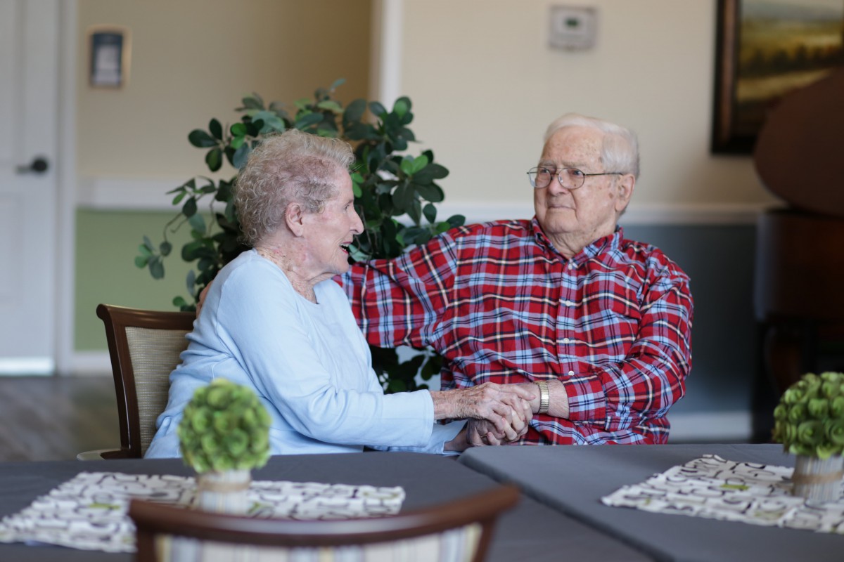 An elderly couple smiling and enjoying each other's company indoors.