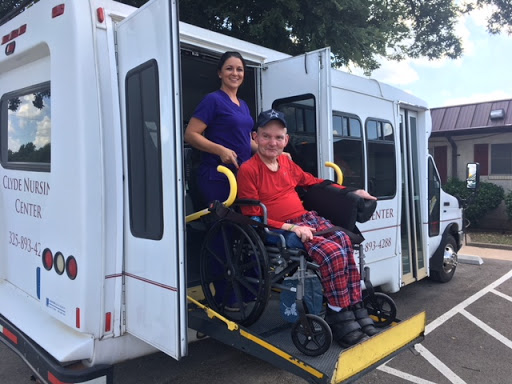 A caregiver assists a person in a wheelchair exiting a vehicle, highlighting the importance of accessible transportation.