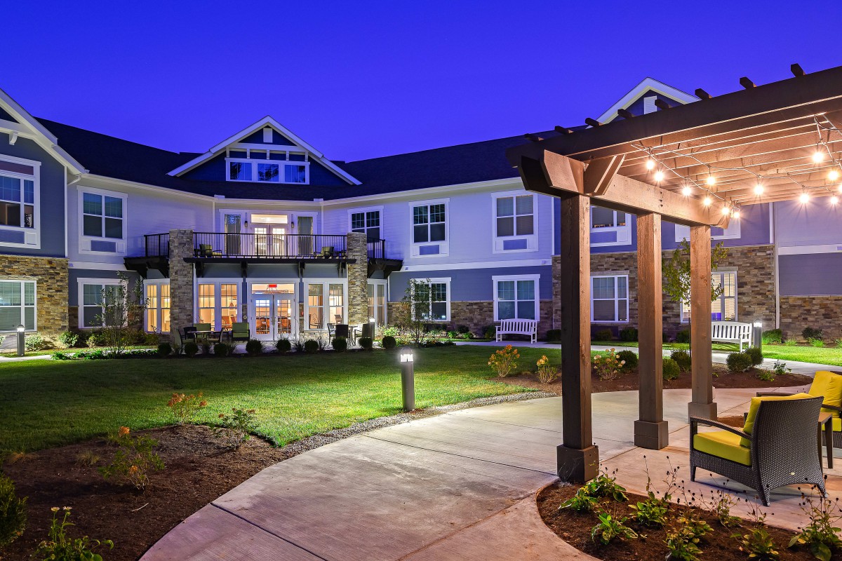 A well-lit residential building with a landscaped pathway at night.