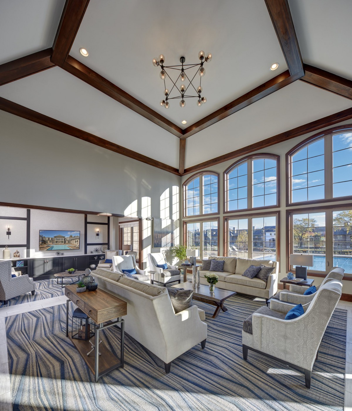 A spacious and modern living room with high ceilings, large windows, and stylish furniture.