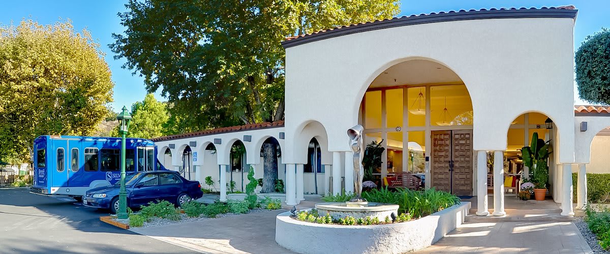A Mediterranean-style house featuring prominent arches, a courtyard garden, and a central statue.