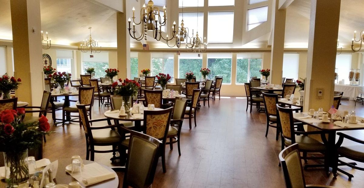 An elegant dining room with chandeliers, large windows, and neatly arranged tables and chairs.