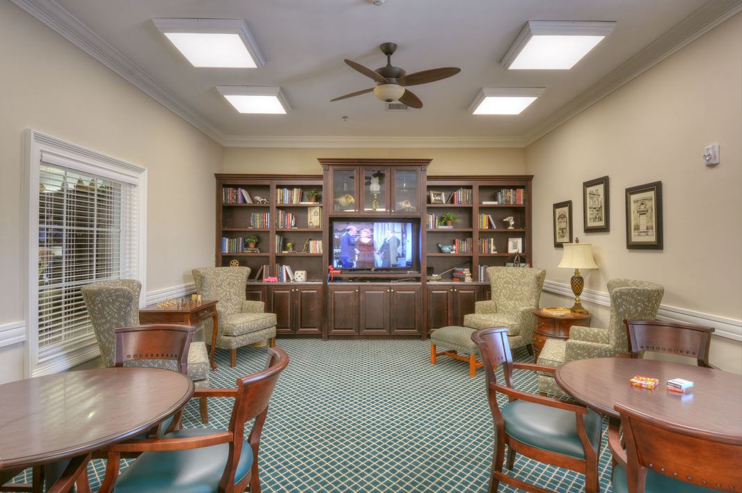 A cozy library room featuring bookshelves, a television, and comfortable seating.
