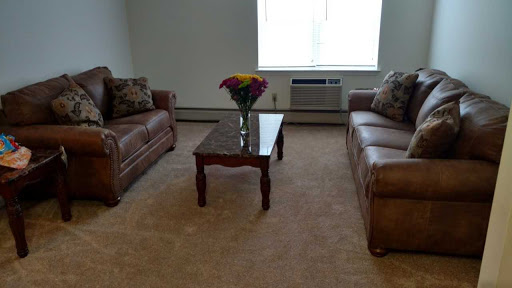 A cozy living room featuring two leather sofas, a coffee table, and a bouquet of flowers.