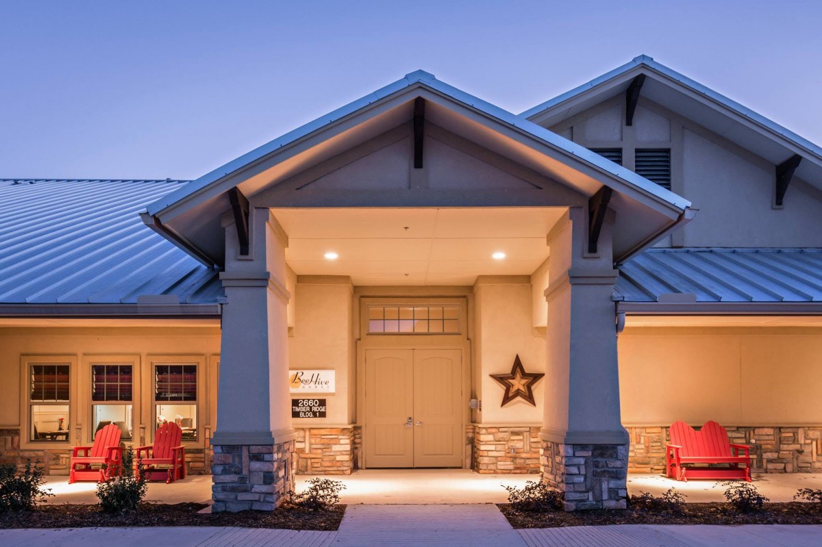 A well-lit residential house with a welcoming front porch during the evening.