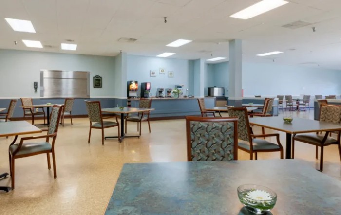 An empty cafeteria with tables and chairs arranged neatly in a spacious dining area.