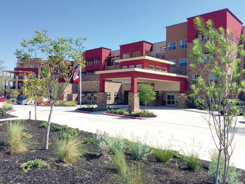 A modern hospital building with landscaped surroundings on a sunny day.