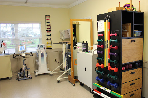 A well-equipped physical therapy room featuring various exercise equipment and weights for rehabilitation.