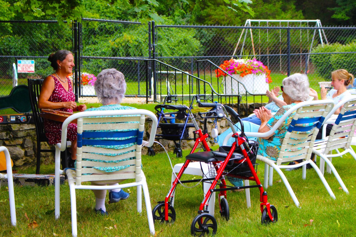 A group of elderly people enjoying a social gathering outdoors in a garden.