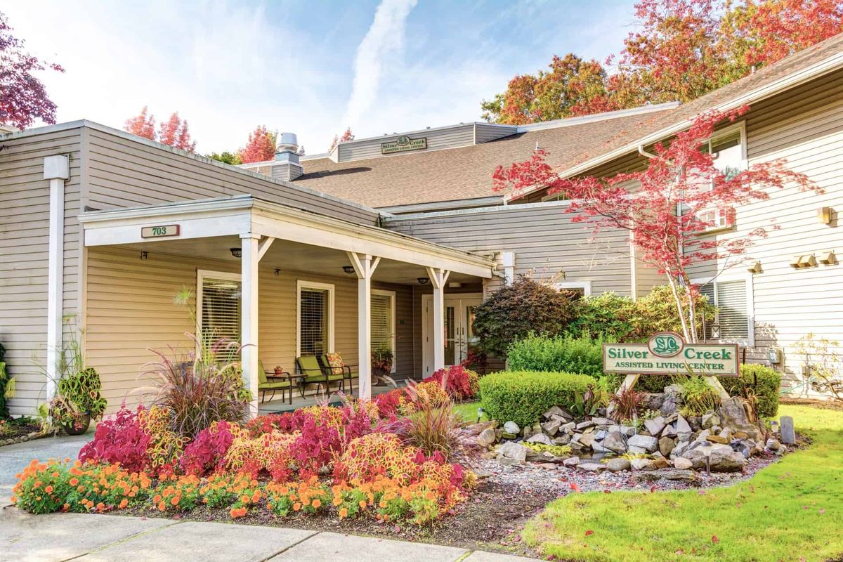 A cozy house surrounded by vibrant autumn foliage and well-kept landscaping.