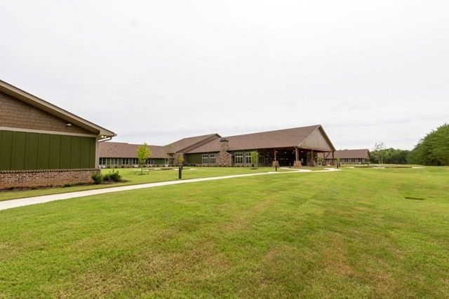 A view of a modern building complex with a large lawn and an overcast sky.