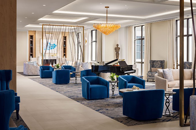 A luxurious lounge area with modern blue chairs, a grand piano, and stylish decor.