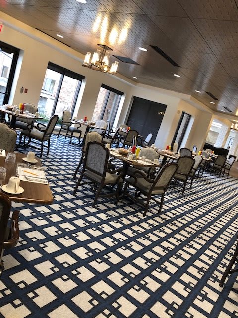 An elegant restaurant dining area with neatly arranged tables and chairs on a patterned carpet.