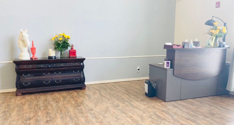 A simple reception area with a desk and flowers on display.