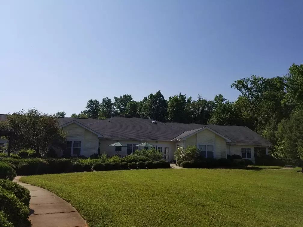 A suburban house with a well-maintained lawn and surrounding trees on a clear day.
