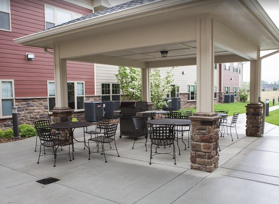 Outdoor patio area with seating and a grill under a pergola.