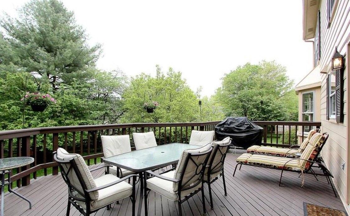 A cozy patio with a dining set and grill surrounded by lush greenery.