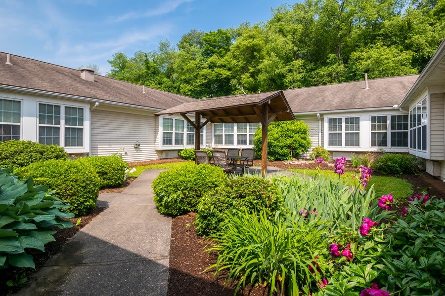 A charming house with a well-maintained garden and patio area surrounded by lush greenery.