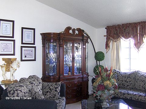 A living room with a decorative cabinet, floral arrangement, and natural lighting.