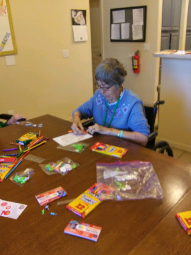 An elderly woman engaging in a creative arts and crafts activity at a community center.