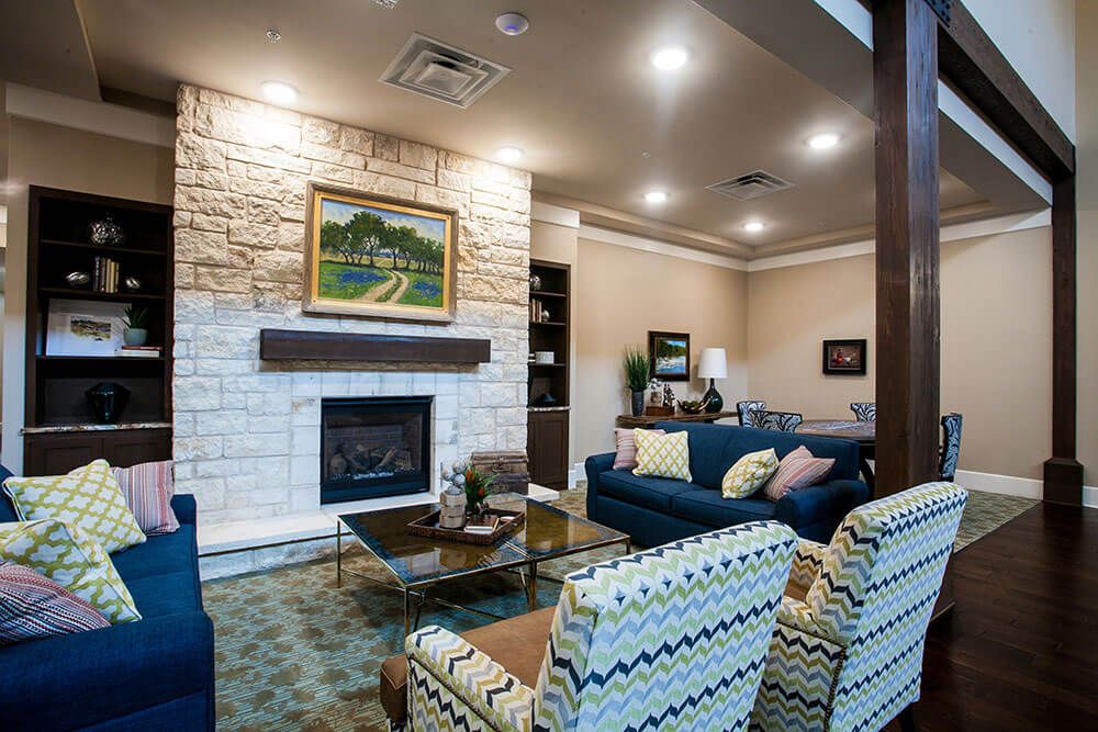 A cozy living room featuring a stone fireplace, comfortable seating, and tasteful artwork.
