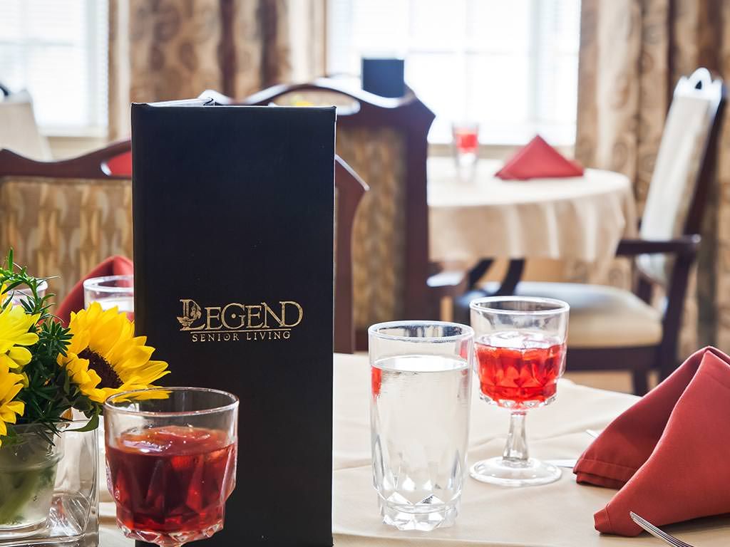 A cozy restaurant table setting with a menu, drinks, and a sunflower centerpiece.