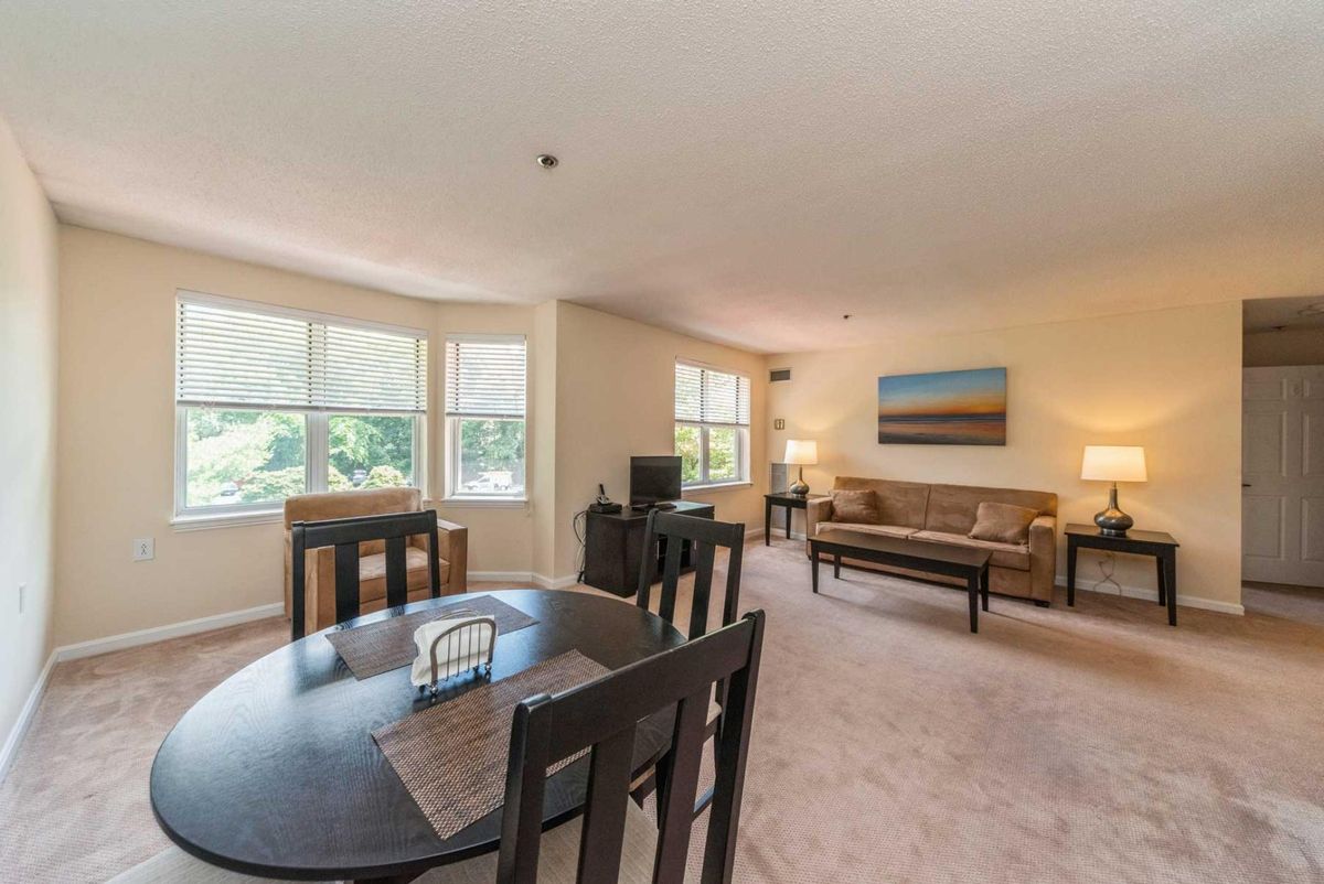 A spacious living and dining area with large windows, comfortable seating, and tasteful artwork.