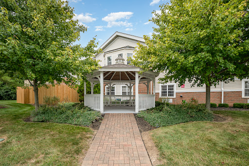A charming house featuring a gazebo surrounded by lush greenery and a brick pathway.